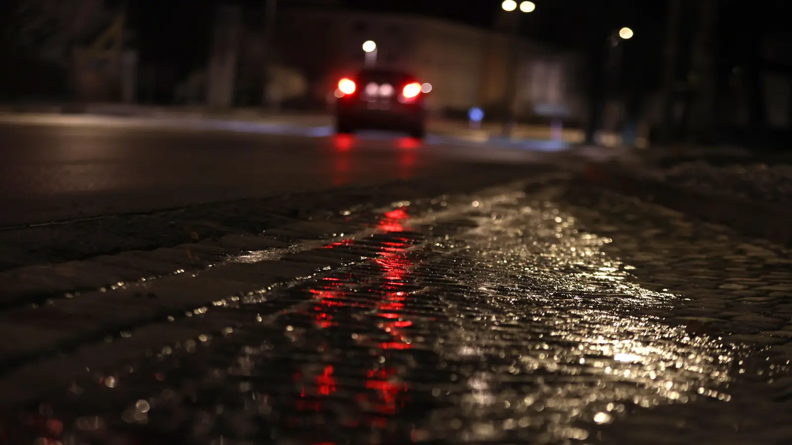 Eine Straße ist mit einer dünnen Eisschicht überzogen. In Amberg und im Landkreis Amberg-Sulzbach gab es zahlreiche Unfälle während der Glätte. (Symbolbild: Karl-Josef Hildenbrand /dpa)