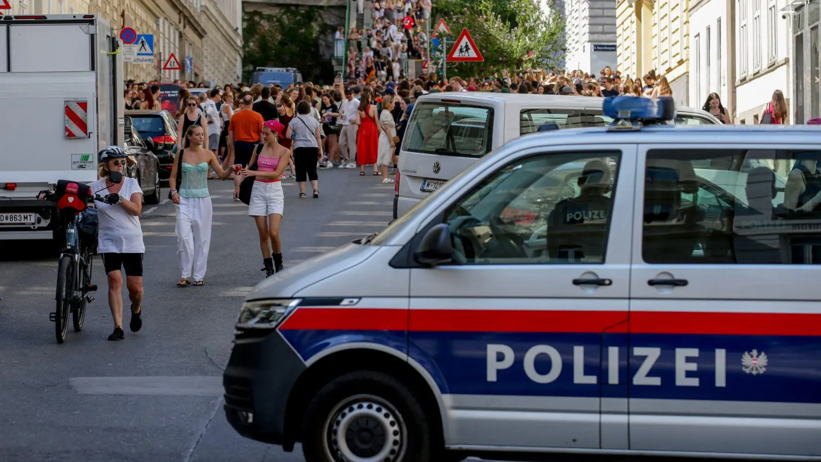 Ein Polizeiauto steht in der Nähe von versammelten „Swifties“, nachdem im Sommer 2024 Konzerte abgesagt wurden aus Angst vor einem Terroranschlag. (Archivbild)  (Bild: Heinz-Peter Bader/AP/dpa)