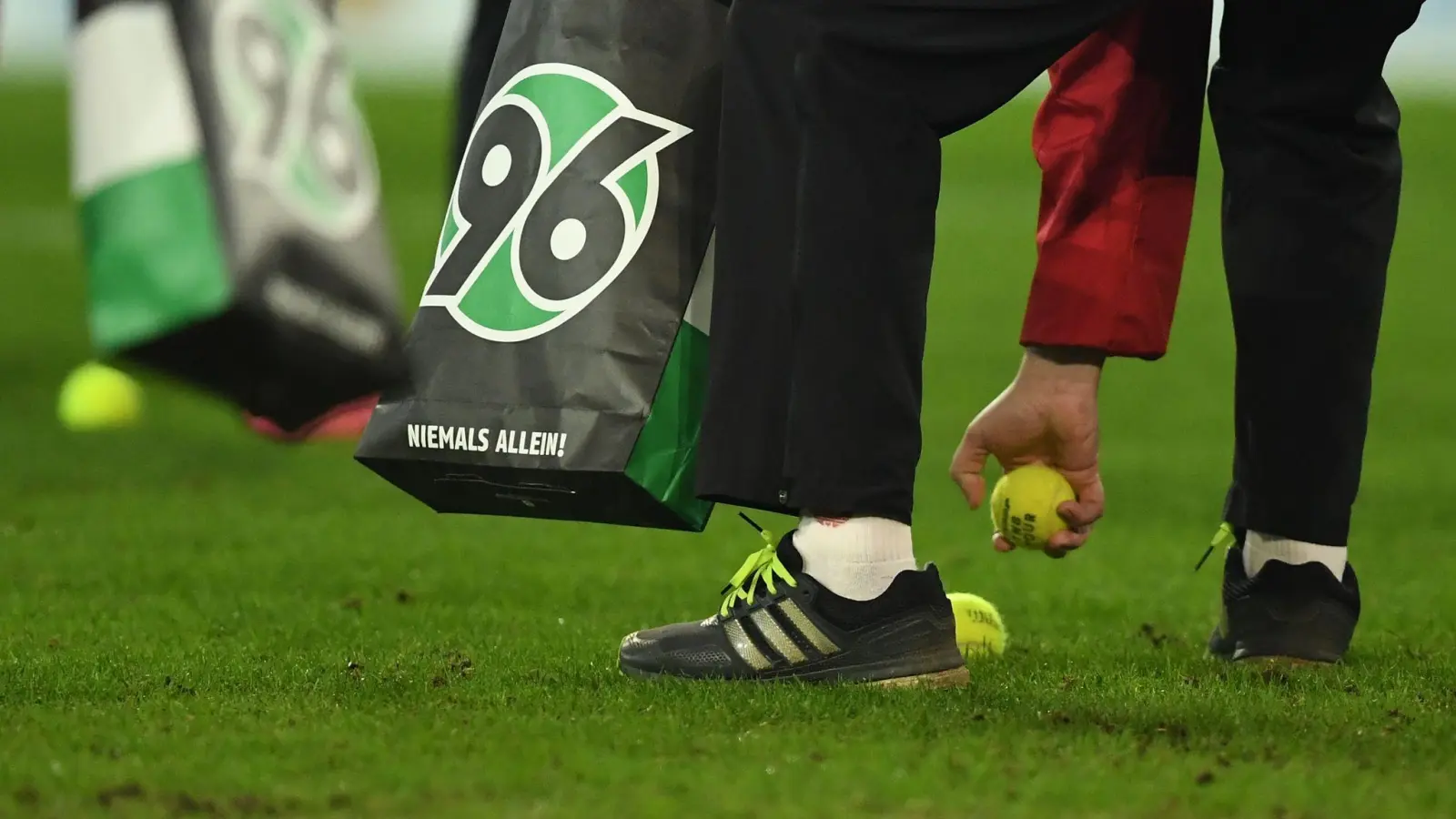 Helfer sammeln Tennisbälle vom Spielfeld. (Bild: Swen Pförtner/dpa)