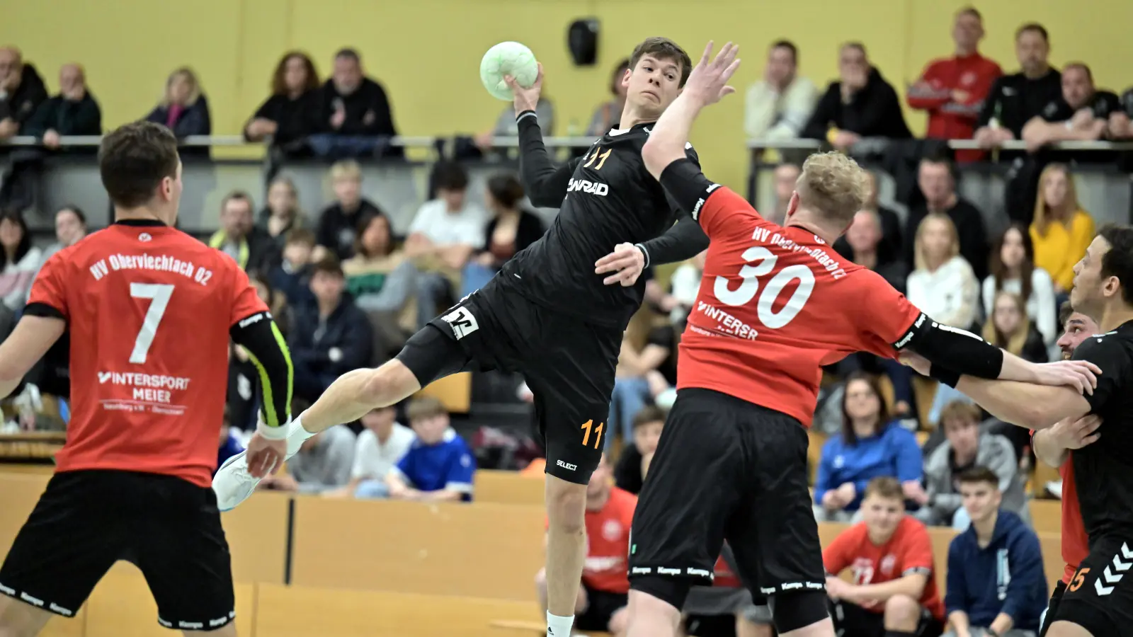Julian Schaller (am Ball) von der HG Amberg kann in dieser Szene aus dem Rückraum ein Tor für seine Mannschaft erzielen. Mannschaftskollege Ahmed Arrak (rechts) beobachtet die Aktion, während die Oberviechtacher Jannik Uschold und Patrick Schießl (rote Trikots, von links) keine Abwehrchance haben. (Bild: Hubert Ziegler)