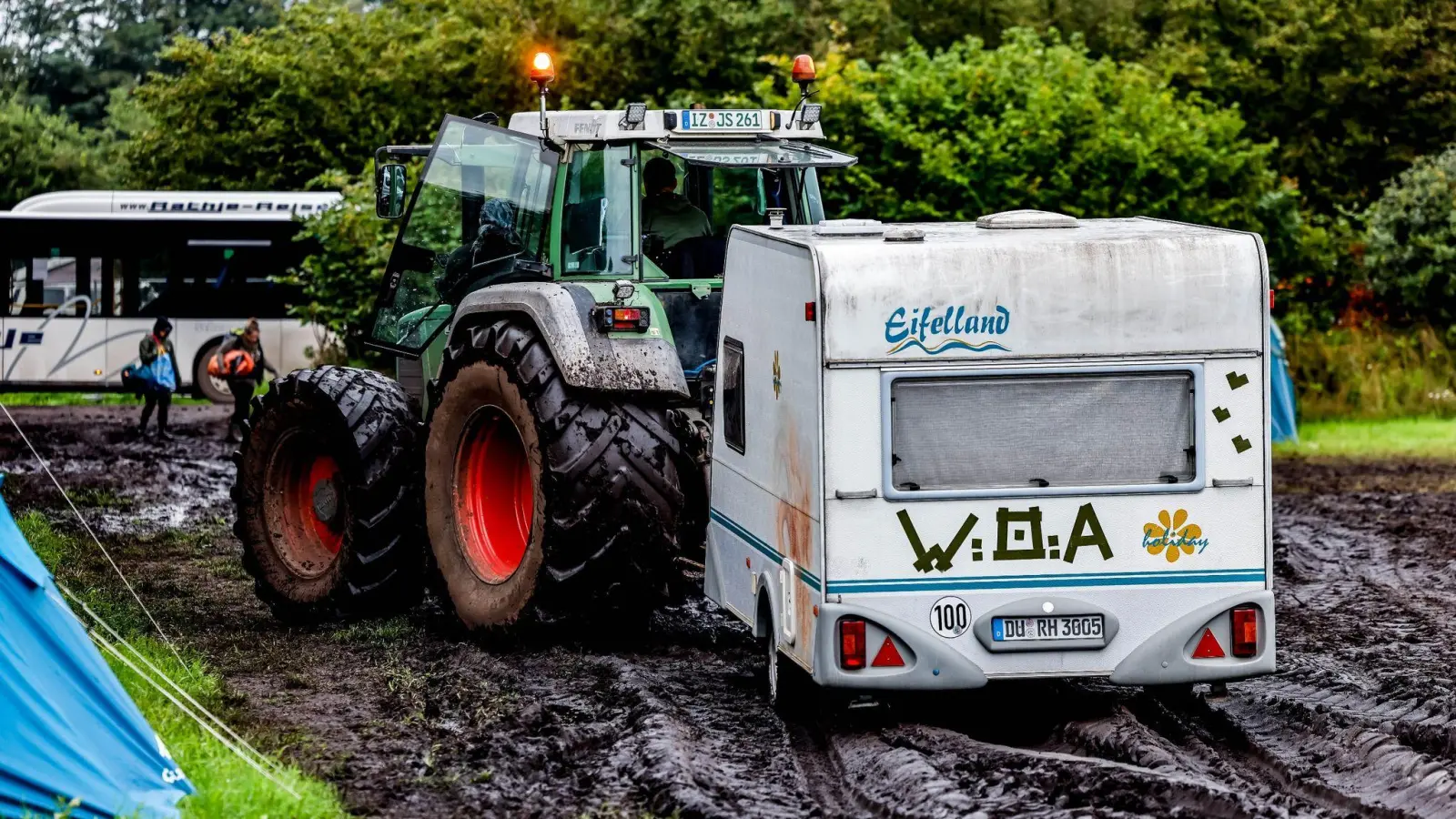 Ab durch den Schlamm:&nbsp;Ein Traktor zieht einen Wohnwagen vom Campinggelände des Wacken Open Air. (Bild: Axel Heimken/dpa)