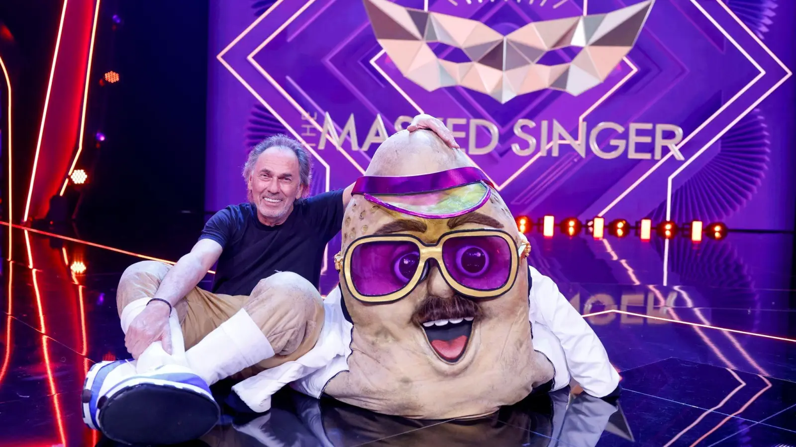 Hugo Egon Balder, Moderator, sitzt als enttarnte Figur „Der Couchpotato“ in der Prosieben-Show „The Masked Singer“ auf der Bühne. (Bild: Thomas Banneyer/dpa)