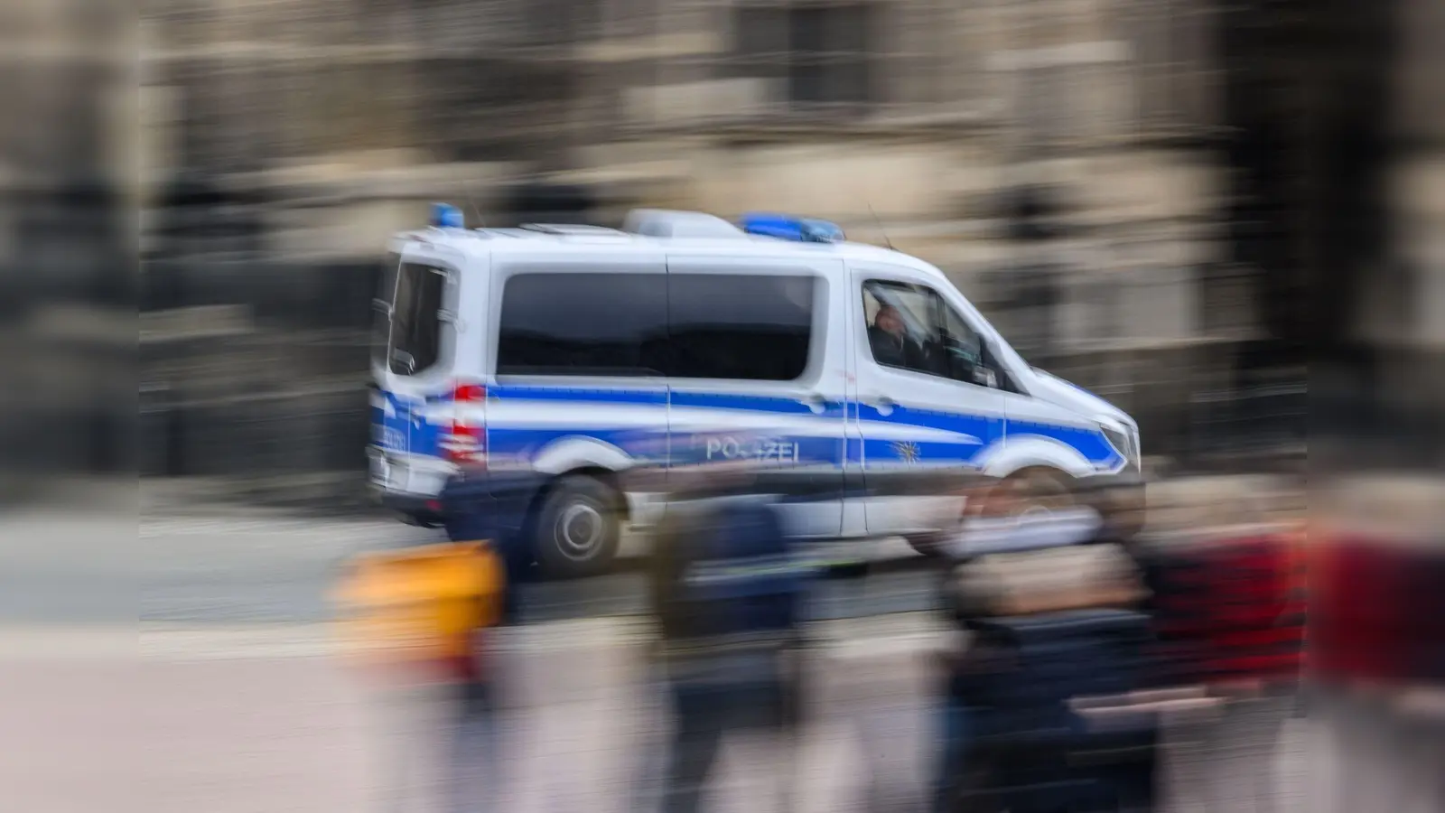 Ein Einsatzwagen der Polizei fährt durch eine Stadt. (Bild: Robert Michael/dpa/Symbolbild)