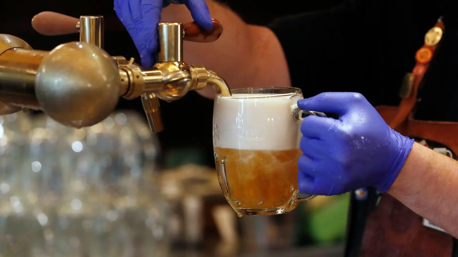 Ein Barkeeper zapft ein Bier auf einer Restaurant-Terrasse. (Symbolbild: Petr David Josek/AP/dpa)