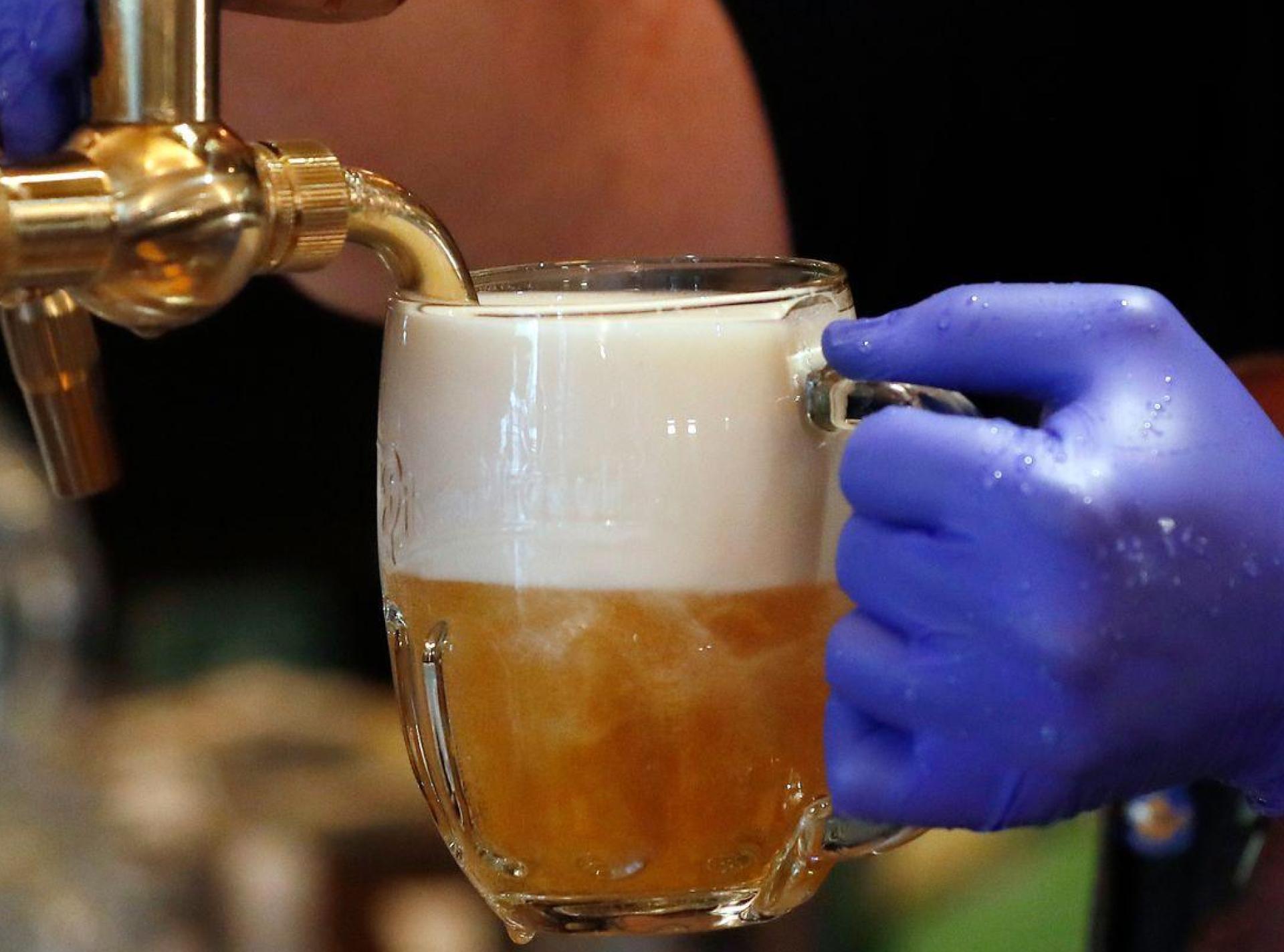Ein Barkeeper zapft ein Bier auf einer Restaurant-Terrasse. (Symbolbild: Petr David Josek/AP/dpa)