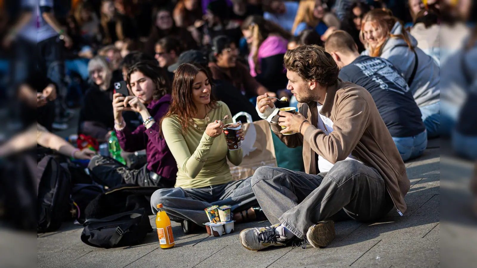 Zahlreiche Menschen treffen sich am Küchengarten, einem Platz in Hannover, um Pudding mit Gabeln zu essen.  (Bild: Moritz Frankenberg/dpa)