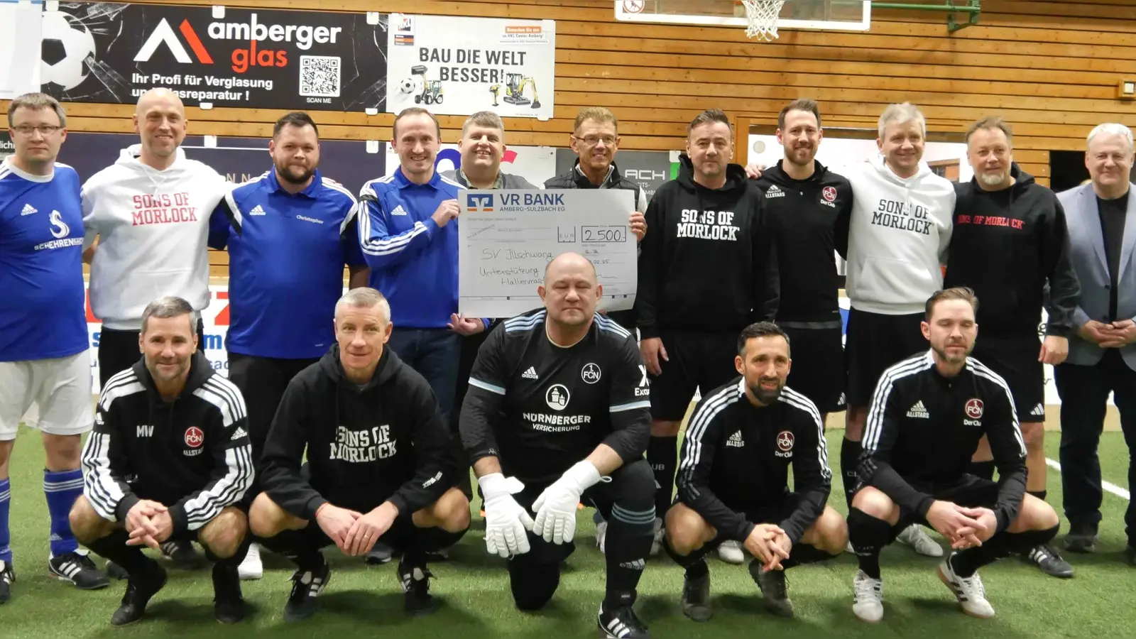 Die Traditionsmannschaft des 1. FC Nürnberg mit Teamchef Thomas Ziemer (stehend, Fünfter von rechts) und dem früheren Bundesliga-Torschützenkönig Marek Mintal (knieend, Zweiter von links) gesellt sich bei der Übergabe des 2500 Euro schweren Spendenschecks der VR-Bank an den SV Illschwang dazu. (Bild: no)