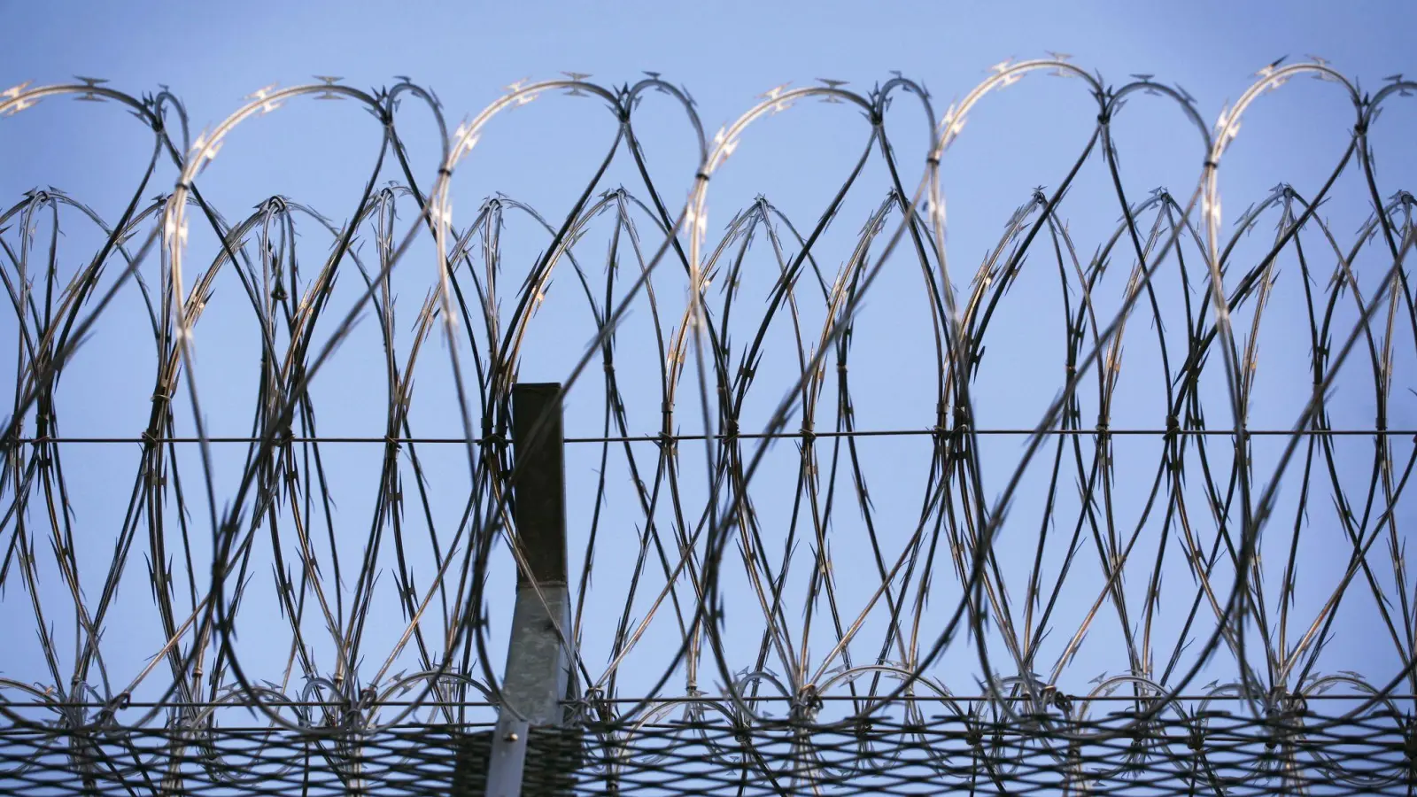 Stacheldraht krönt den Zaun eines Gefängnisses. In Landshut verhindert eine Spezialeinheit der Polizei die Befreiung eines Gefangenen. (Symbolbild: Wolfram Steinberg/dpa)