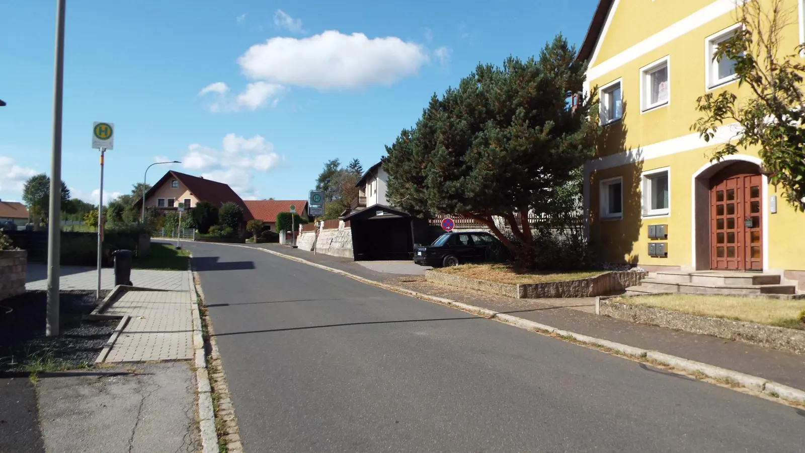 Das alte Buswartehäuschen (rechts) in der Schweppermannstraße (hinten) wird erneuert, die Haltestelle (links vorne) wird nach hinten verlegt. Auf beiden Seiten wird der Gehweg verbreitert , die Rasenfläche (vorne rechts) wird verkleinert.  (Bild: e)