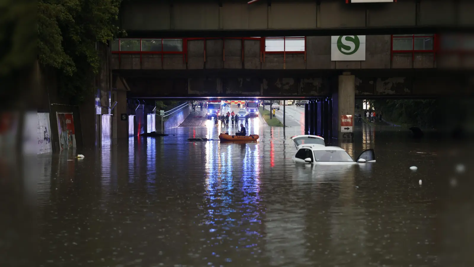 Einsatzkräfte der Feuerwehr können nur noch mit einem Schlauchboot zu den Autos in einer überschwemmten Unterführung gelangen.  (Bild: Oßwald/News5 /dpa)