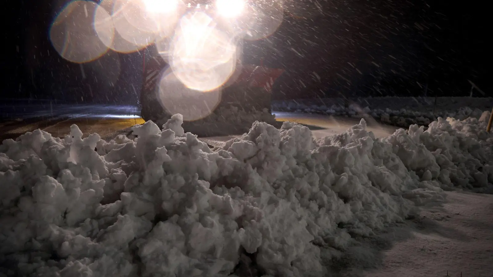 Ein Räum- und Streufahrzeug des Winterdienstes räumt am frühen Morgen im Ortsteil Oberjoch Schnee von einem Parkplatz. (Bild: Karl-Josef Hildenbrand/dpa)