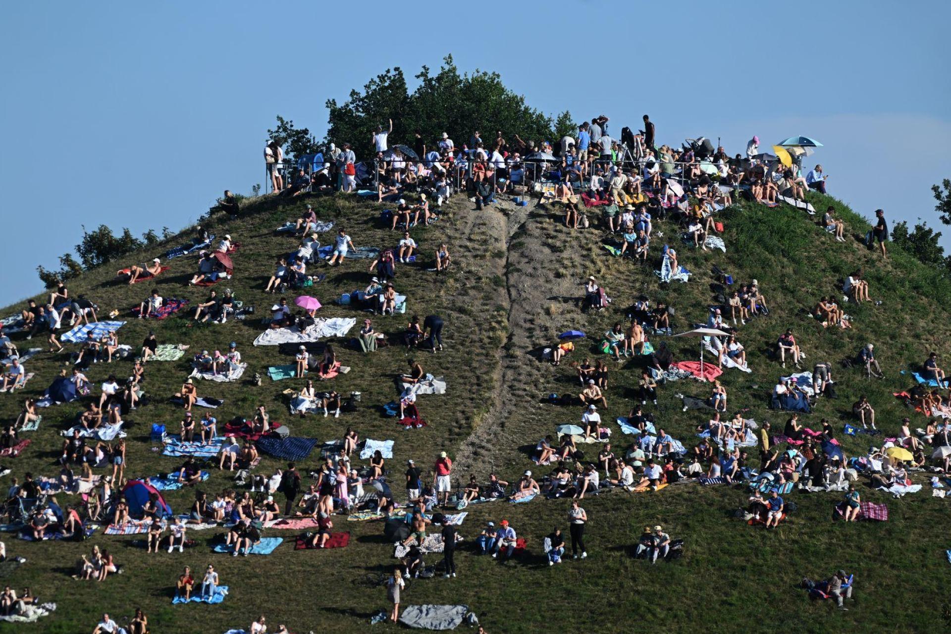 Erste Besucher bevölkern den Olympiaberg im Münchner Olympiapark, um von dort die partielle Sonnenfinsternis zu beobachten. (Bild: Felix Hörhager/dpa)