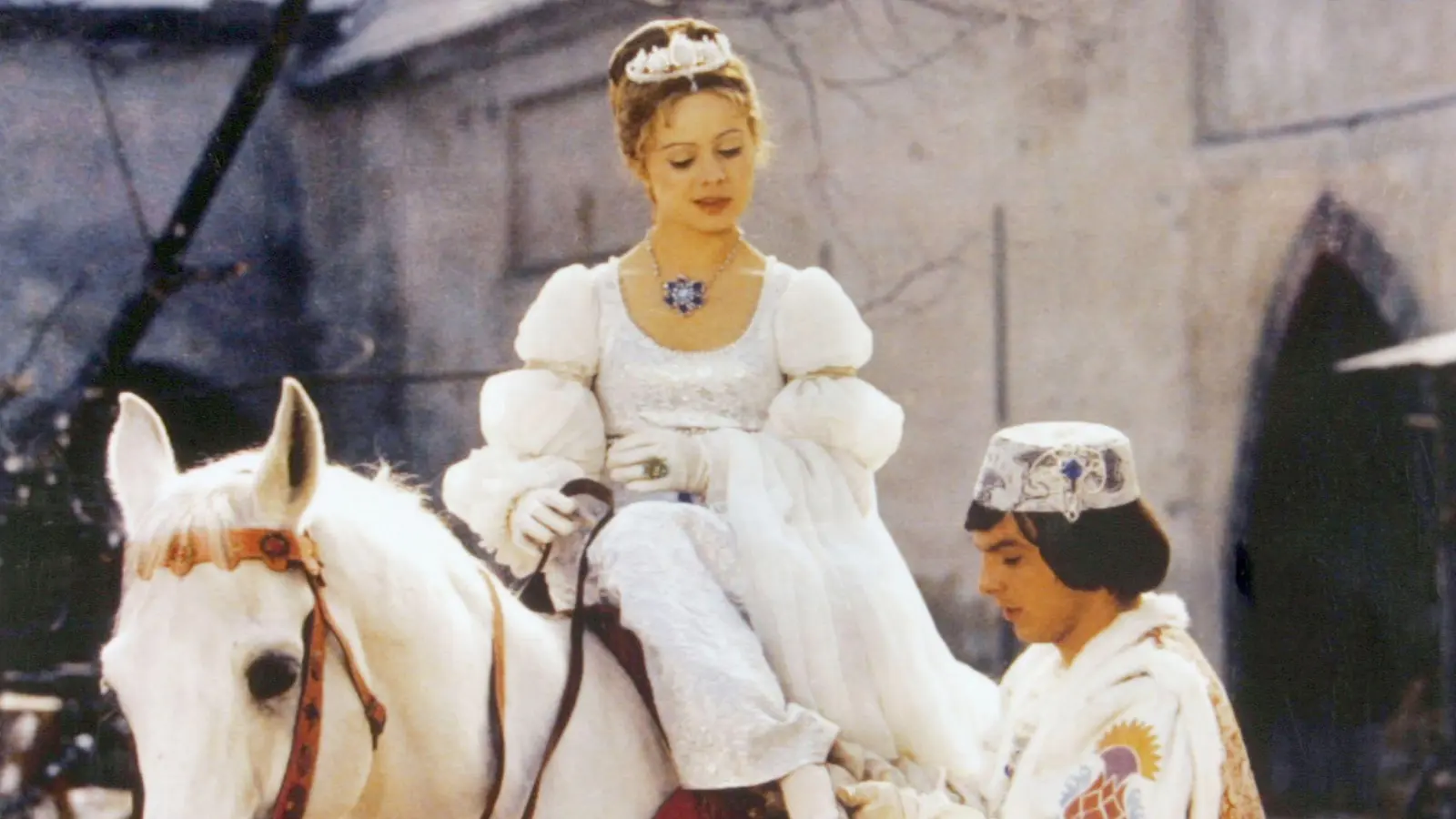 Der Prinz (Pavel Trávnícek) passt Aschenbrödel (Libuse Safránková) den verlorenen Schuh an. (Filmszene) (Bild: Degeto/WDR/dpa)