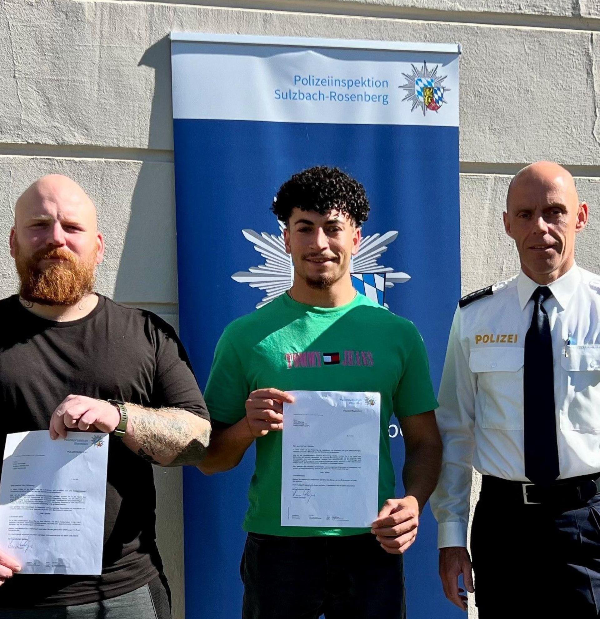 Polizeihauptkommissar Tobias Plößl (rechts), stellvertretender Leiter der Polizeiinspektion Sulzbach-Rosenberg, zeichnet zwei couragierte Bürger aus: Merlin Scharnagl (links) und Abud Alhamad (Mitte) hatten der Polizei geholfen, einen Randalierer im Regionalexpress festzunehmen. (Bild: PI Sulzbach-Rosenberg/exb)
