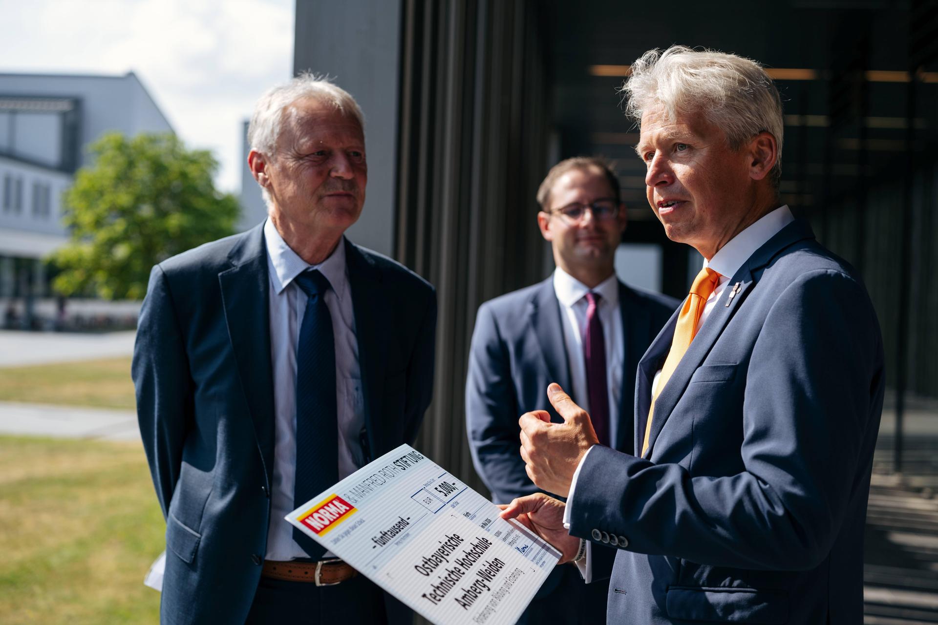 Hochschulpräsident Prof. Dr. Clemens Bulitta (r.) tauscht sich bei der Spendenübergabe unter anderem mit dem Niederlassungsleiter von Norma in Regenstauf, Anton Gleixner (l.), zum dualen Studium an der OTH Amberg-Weiden aus. (Bild: Jolanda Selting/ OTH Amberg-Weiden)