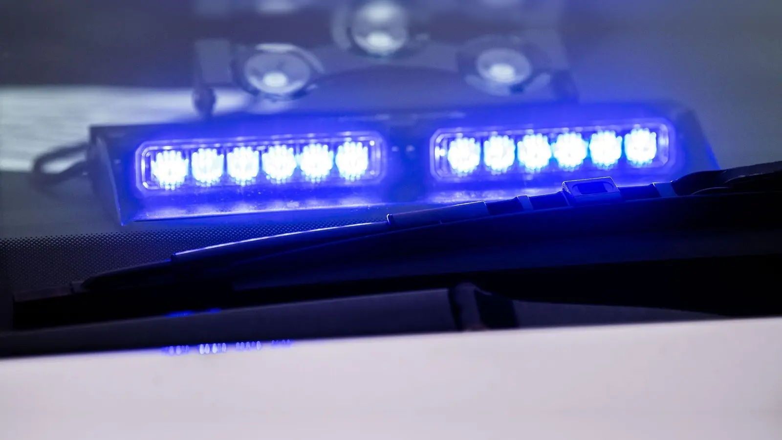 Ein Blaulicht leuchtet unter der Frontscheibe eines Einsatzfahrzeugs der Polizei. (Bild: Lino Mirgeler/dpa/Symbolbild)