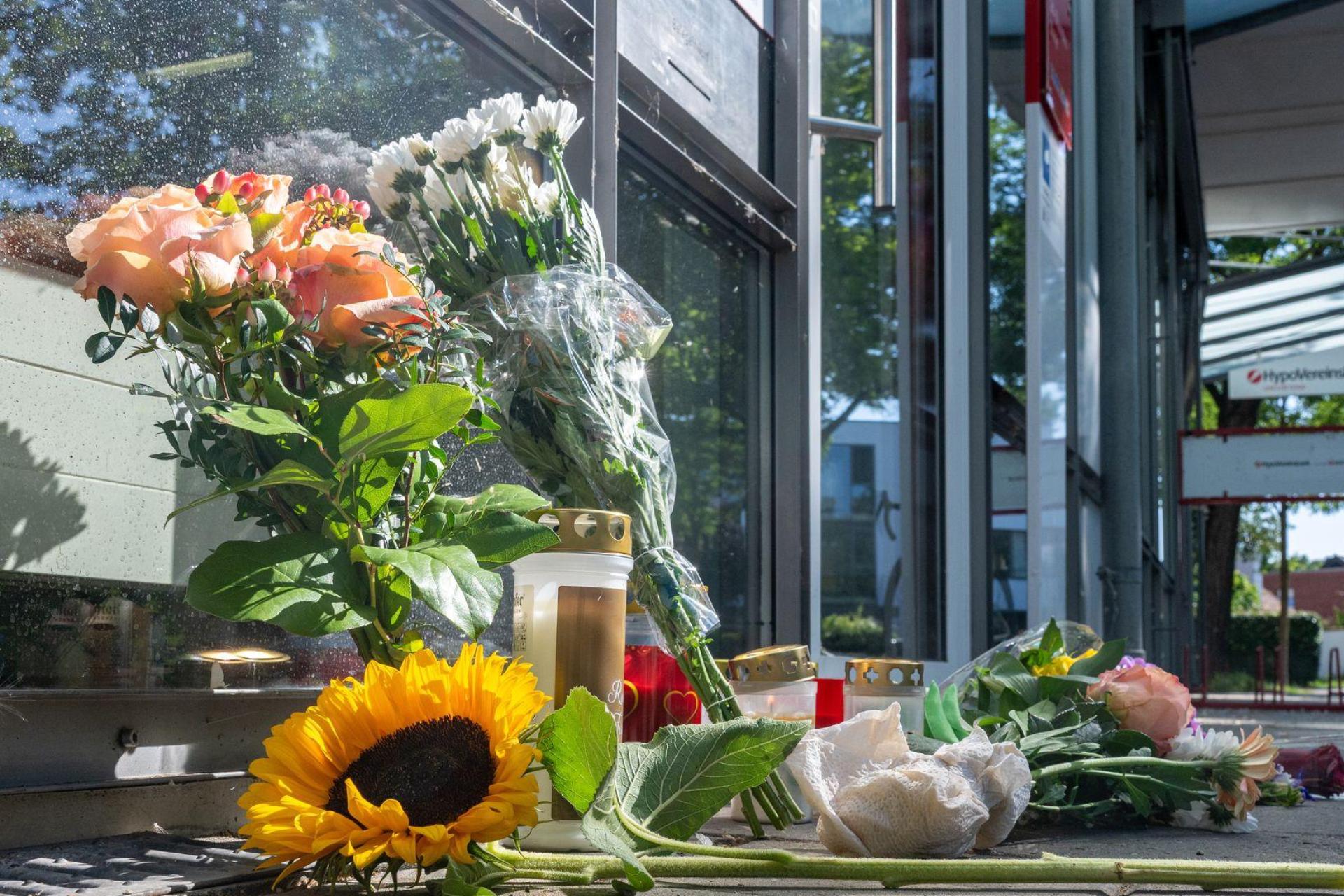 Menschen legten nach dem tödlichen Angriff Blumen und Kerzen vor der Filiale ab. (Bild: Armin Weigel/dpa)