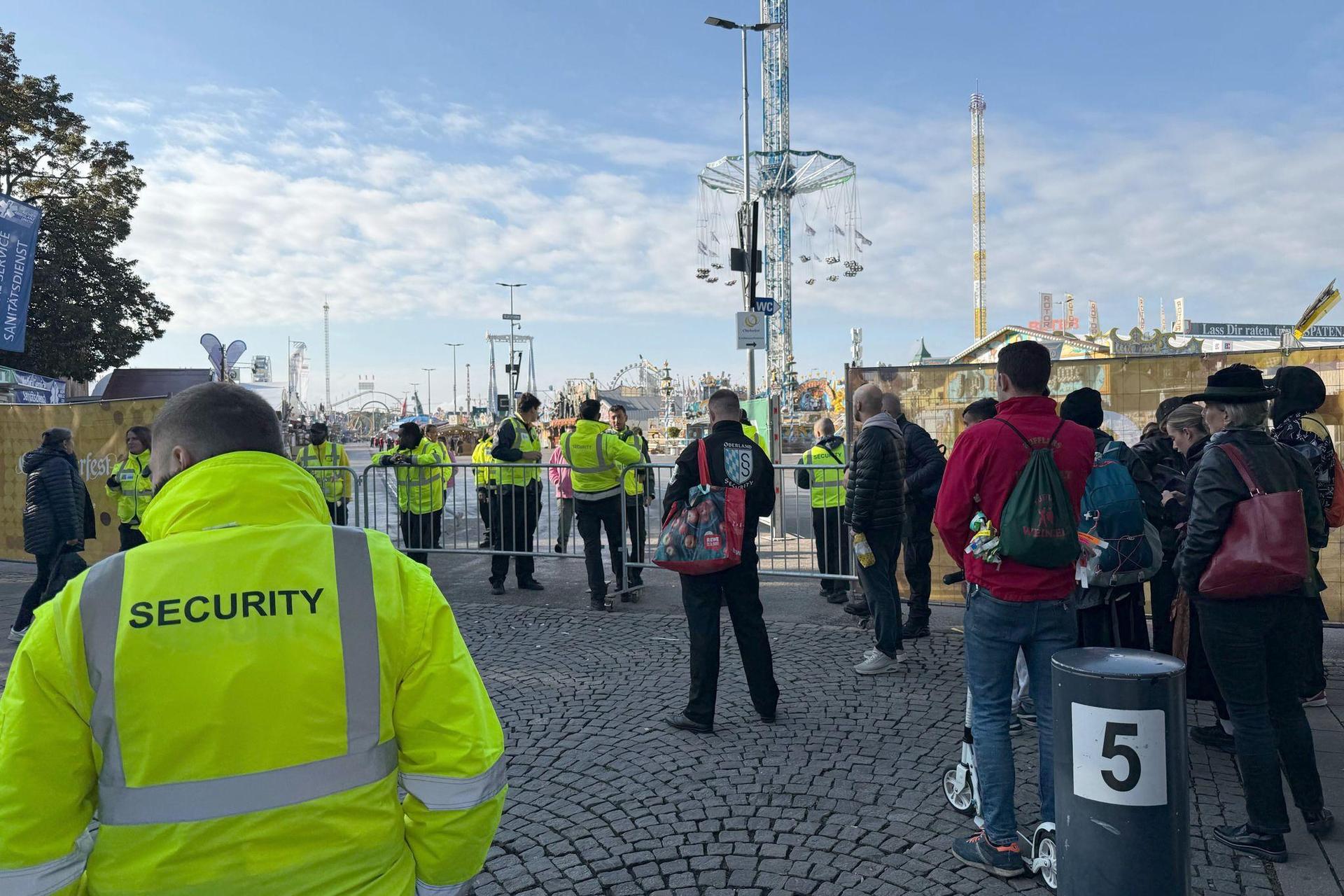 Menschen stehen an einer Absperrung an einem Eingang zum Oktoberfest. Das Münchner Oktoberfest bleibt wegen einer Sprengstoffdrohung bis mindestens 17.00 Uhr geschlossen. (Bild: Manuel Schwarz/dpa)