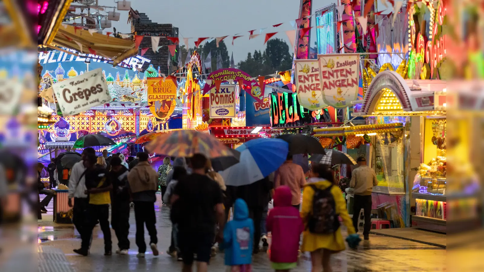 Besucher gehen über das Nürnberger Herbst-Volksfest. (Bild: Daniel Karmann/dpa)