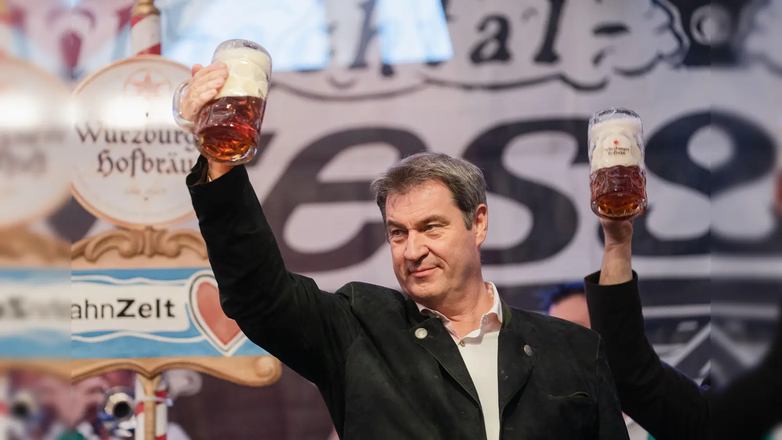 Der bayerische Ministerpräsident Markus Söder (CSU) hält auf der Bühne im Festzelt des Würzburger Frühlingsvolksfestes eine Maß Bier in der Hand. (Bild: Nicolas Armer / dpa)