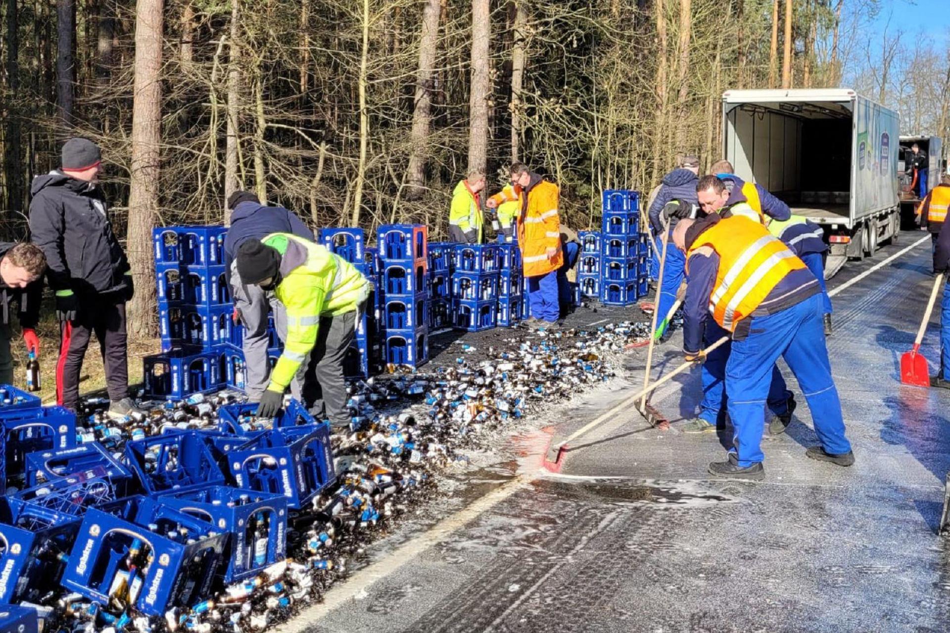 Mitarbeiter räumen Bierkästen und kaputte Flaschen einer von einem Lkw verlorenen Bierladung von einer Straße. (Bild: Danilo Dittrich/dpa-Zentralbild/dpa)