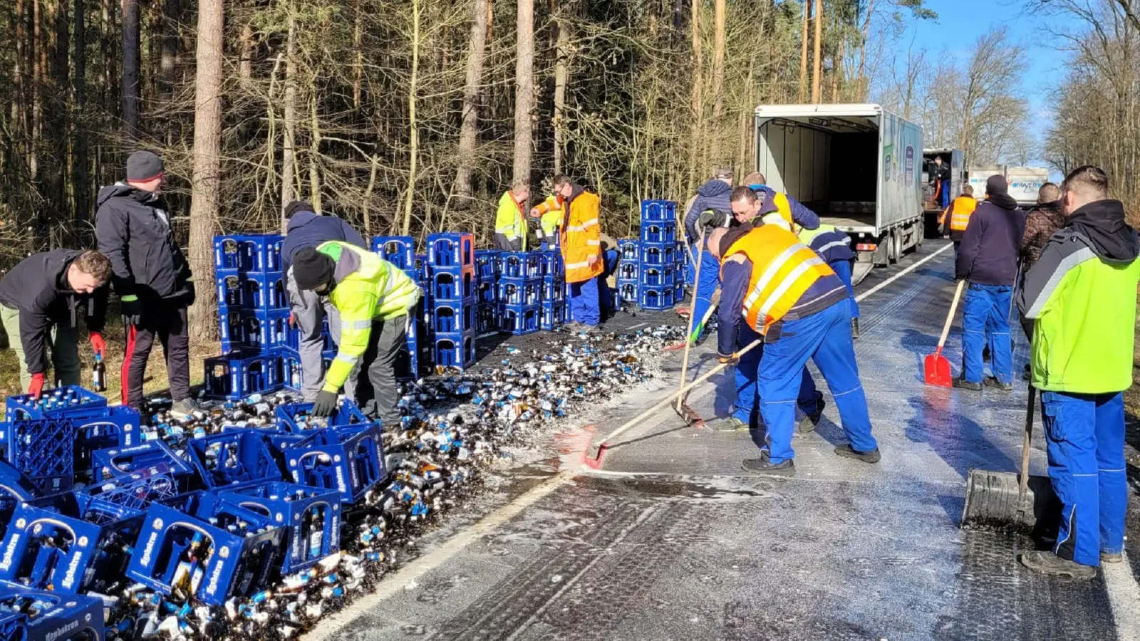 Mitarbeiter räumen Bierkästen und kaputte Flaschen einer von einem Lkw verlorenen Bierladung von einer Straße. (Bild: Danilo Dittrich/dpa-Zentralbild/dpa)