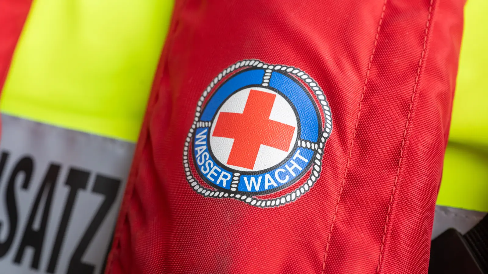 Das Zeichen der Wasserwacht ist auf einer Rettungsweste zu sehen. (Symbolbild: Peter Kneffel/dpa)