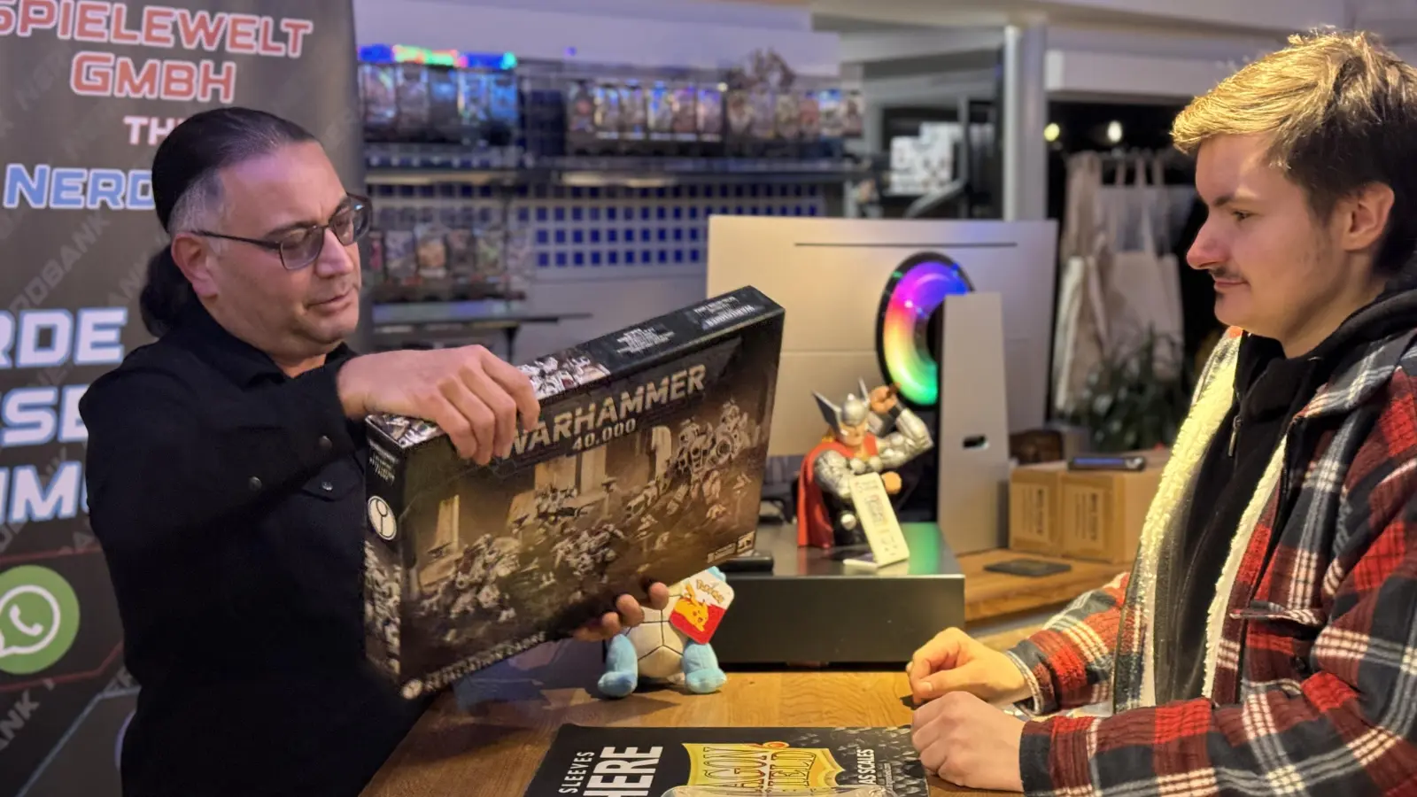 Kunde Denis (rechts) freut sich schon auf sein neues Warhammer 40.000 Set, das Store Manager Ahmet Gürler an ihn übergibt. (Bild: Dominik Mark)